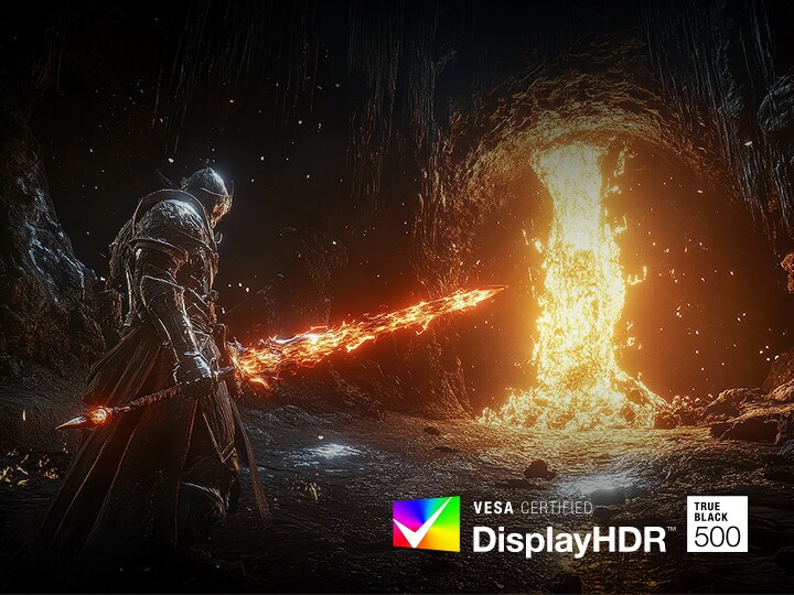 Ένας θωρακισμένος πολεμιστής στέκεται σε ένα σκοτεινό, βραχώδες σπήλαιο, κρατώντας ένα λαμπερό, φλογερό σπαθί. Μπροστά από τον πολεμιστή, ένας τεράστιος χείμαρρος λιωμένης λάβας χύνεται από το ταβάνι της σπηλιάς, ρίχνοντας ένα έντονο πορτοκαλί φως στη σκηνή. Η αντίθεση ανάμεσα στο σκοτάδι της σπηλιάς και την πύρινη φωτιά δίνει έμφαση στο δραματικό και κινηματογραφικό οπτικό στυλ του παιχνιδιού.