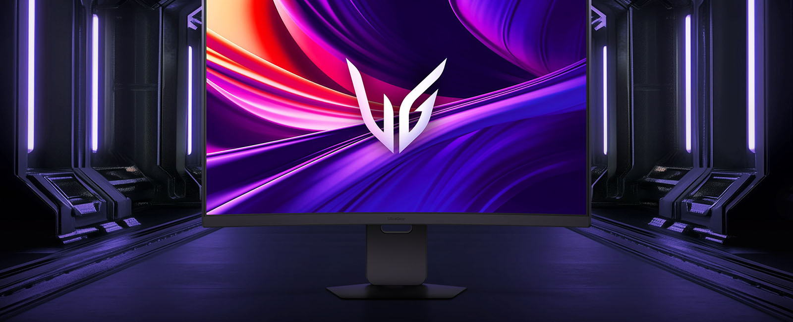 Μπροστινή όψη της οθόνης παιχνιδιών LG UltraGear™ 37G800A στην εξαγωνική βάση της, τοποθετημένη σε έναν φουτουριστικό, διάδρομο με φωτισμό νέον. Η οθόνη δείχνει ζωηρές μοβ και κόκκινες δίνες με το λογότυπο UltraGear™ στο κέντρο.