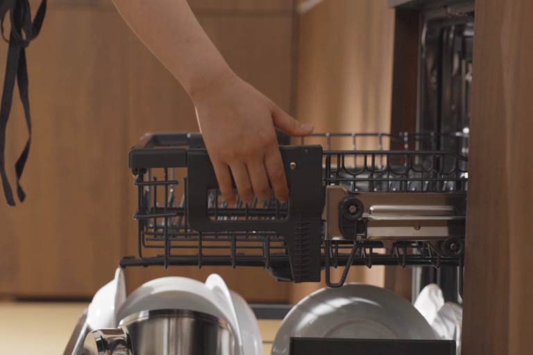 Άτομο σηκώνει το ράφι πλυντηρίου πιάτων LG για να δημιουργήσει χώρο και βάζει μεγάλα σκεύη όπως τηγάνια στο κάτω ράφι.