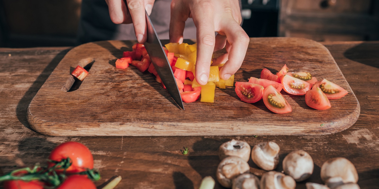 Εικόνα κοπής ντοματών σε επιφάνεια κοπής με μαχαίρι.
