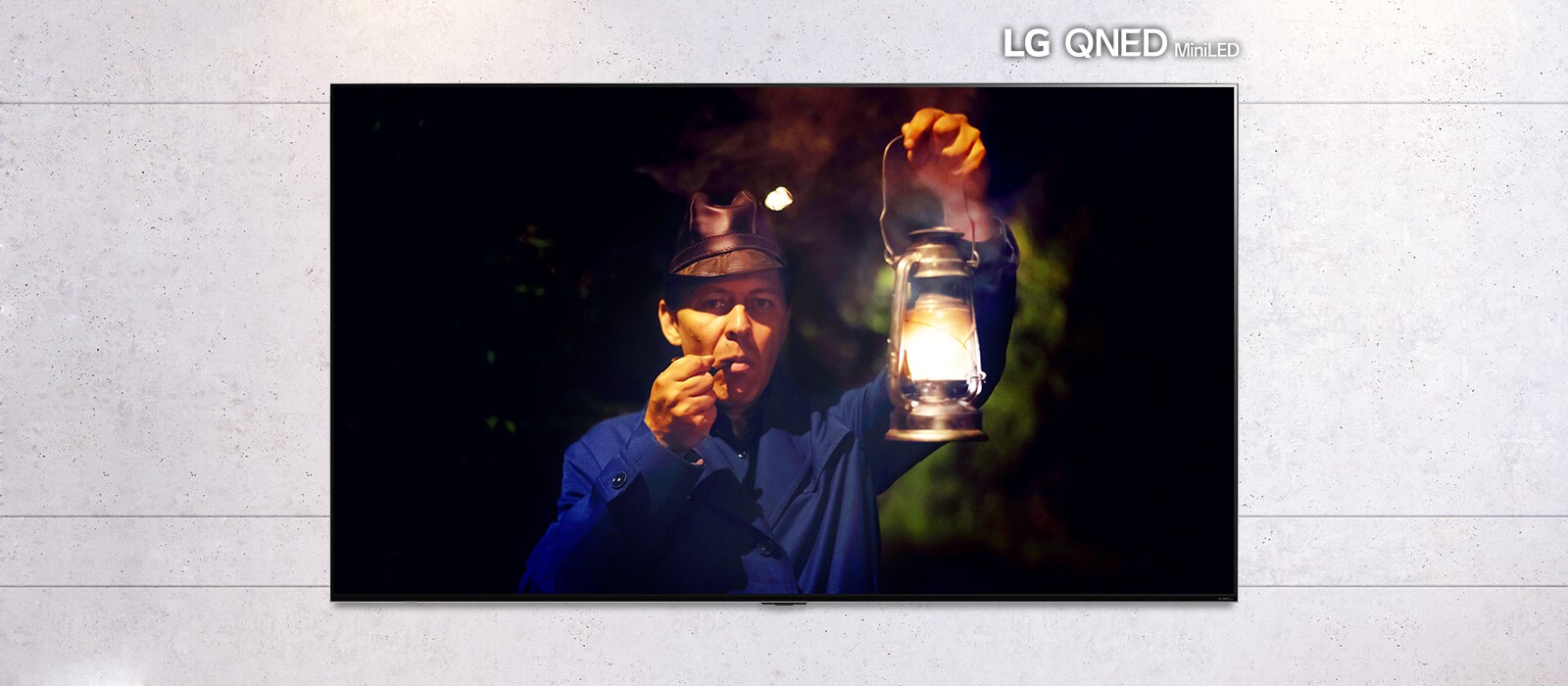 Κυλιόμενη εικόνα μιας επίτοιχης τηλεόρασης, στην οποία απεικονίζεται μια σκοτεινή σκηνή ενός άντρα που κρατά ένα φανάρι. Η σκηνή εναλλάσσεται ανάμεσα σε μια τηλεόραση κανονικού μεγέθους και μια τηλεόραση LG QNED MiniLED με μεγάλη οθόνη.