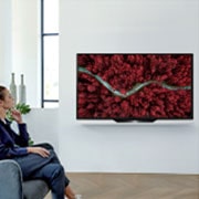 LG BX 65 ίντσες 4K Smart OLED TV, Μια γυναίκα που κάθεται σε μια καρέκλα στο σαλόνι με εναέρια όψη της φύσης στην οθόνη της τηλεόρασης., OLED65BX6LB, thumbnail 13