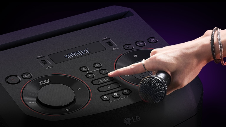 Ruka koja drži mikrofon pokušava pritisnuti tipku Voice Canceller na gornjoj strani sustava LG RNC9.
