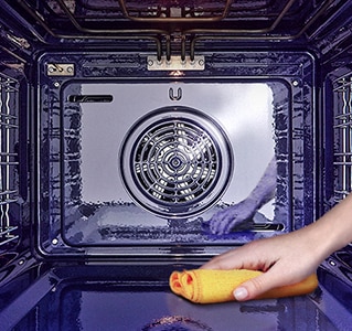 Slika brisanja unutrašnjosti pećnice krpom.