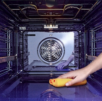 Slika brisanja unutrašnjosti pećnice krpom.