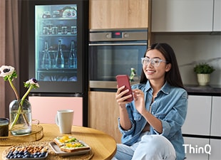 Slika žene koja koristi svoj pametni telefon u kuhinji.