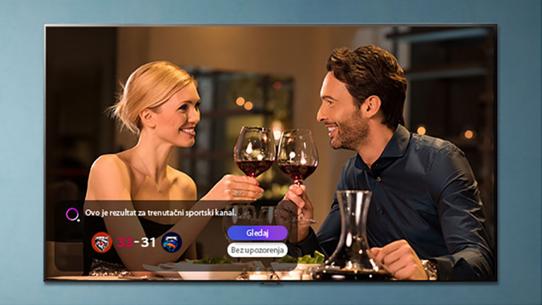 Muškarac i žena nazdravljaju čašama na TV zaslonu dok dolaze obavijesti o sportskim podsjetnicima