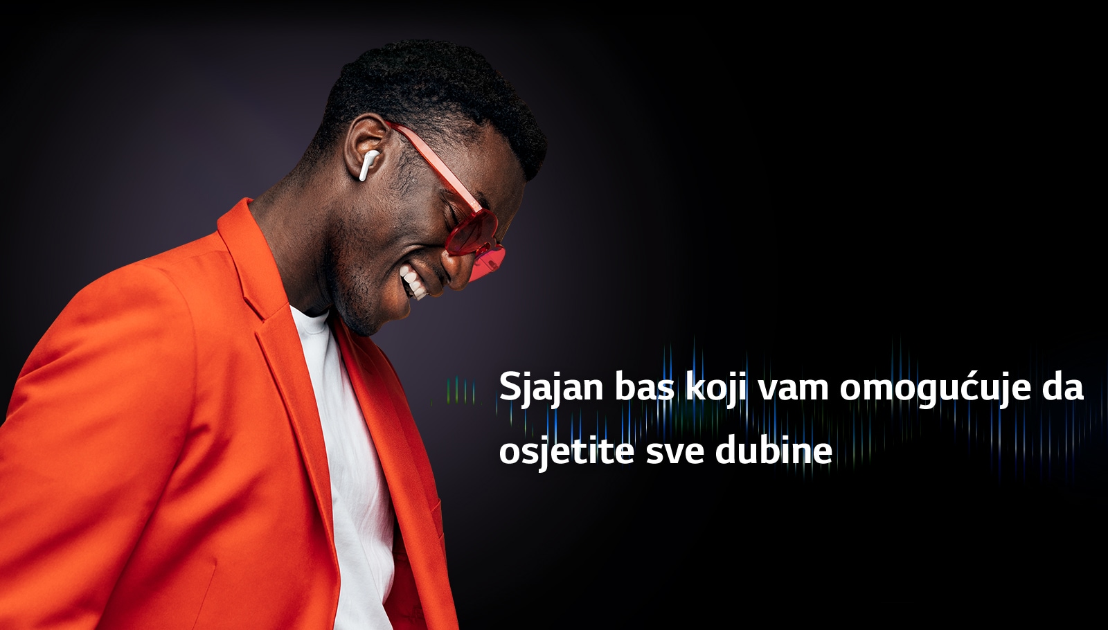 Čovjek u narančastom odijelu sluša glazbu s uključenim slušalicama TONE Free.