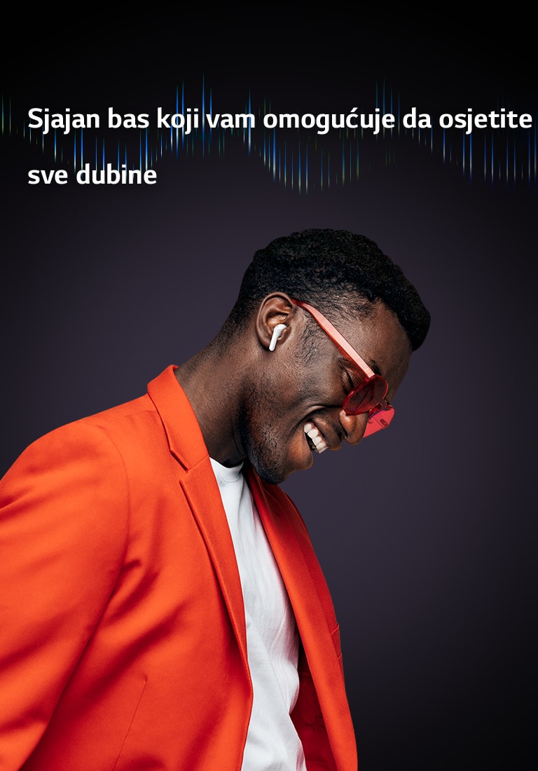 Čovjek u narančastom odijelu sluša glazbu s uključenim slušalicama TONE Free.