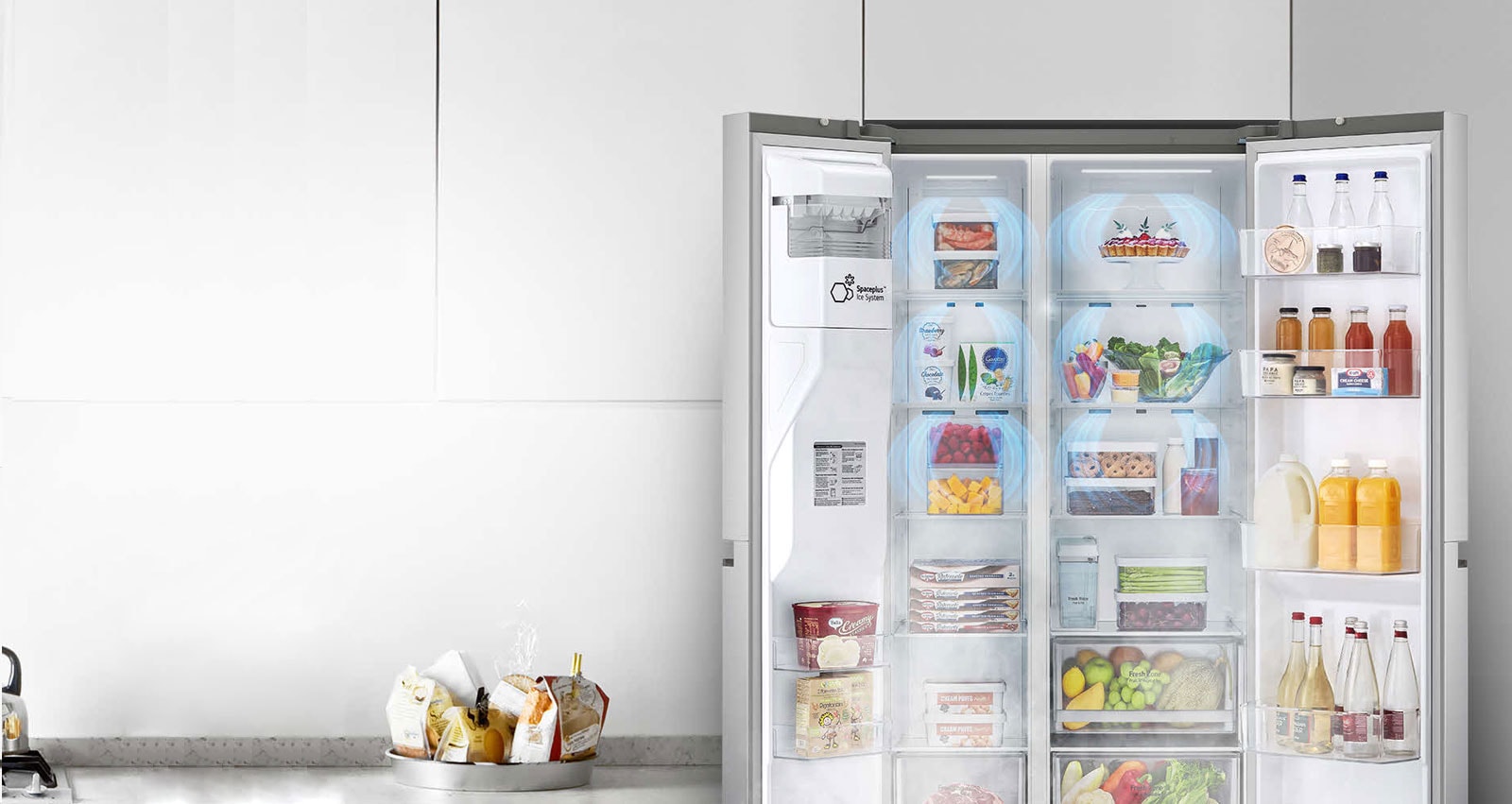 Pogled od spredaj na hladilnik z dvojimi na stežaj odprtimi sprednjimi vrati, ki prikazujejo poln hladilnik.  Prikazani so modri oblaki megle, ki se spuščajo nad vse izdelke.