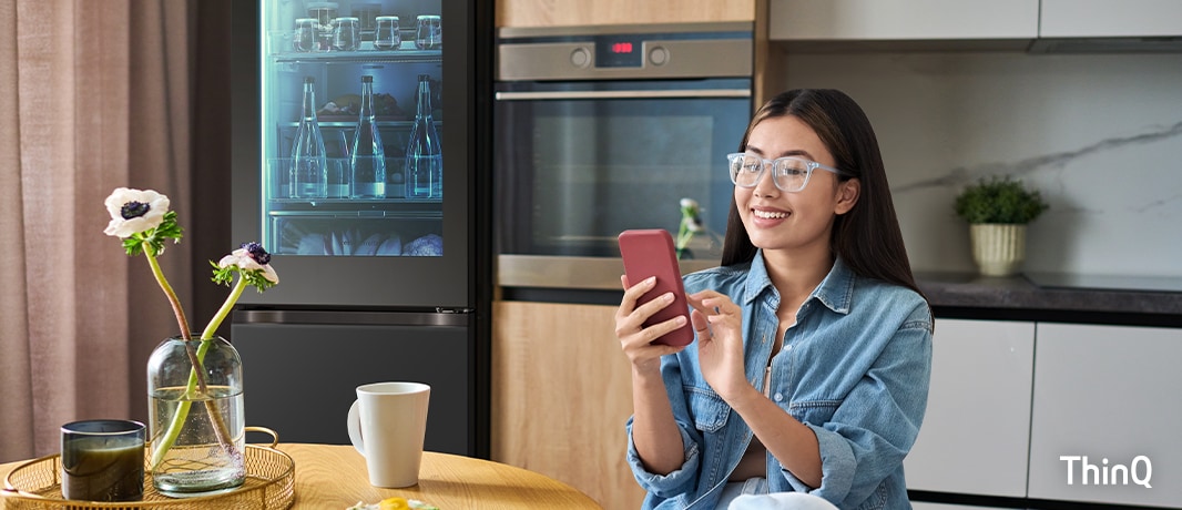 Slika žene koja koristi svoj pametni telefon u kuhinji.