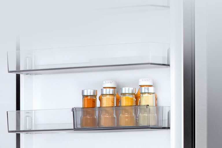 Pogled na unutrašnjost LG hladnjaka s donjim zamrzivačem: šest malih bočica umaka u prozirnom odjeljku s mini vratima s kliznim vratima.