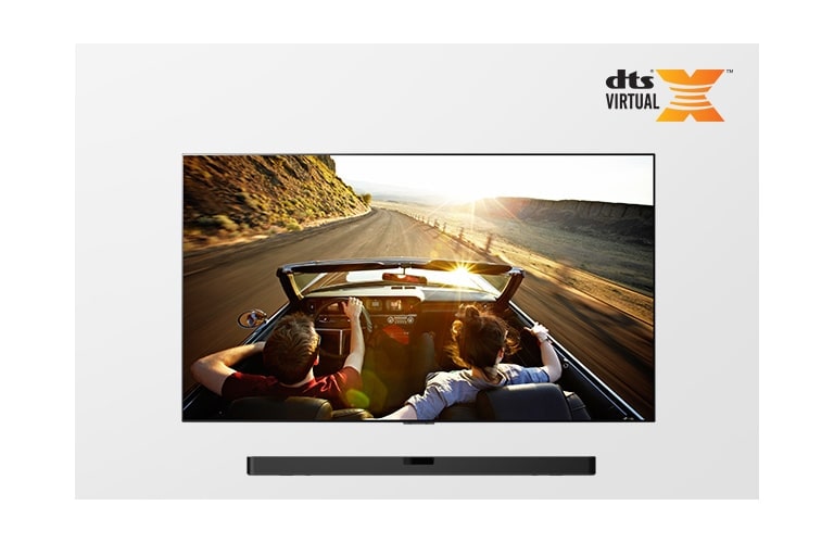 Televizor i zvučnik Sound Bar zajedno u potpunom prikazu. Na televizoru je prikazan par koji se vozi u kabrioletu u suton.