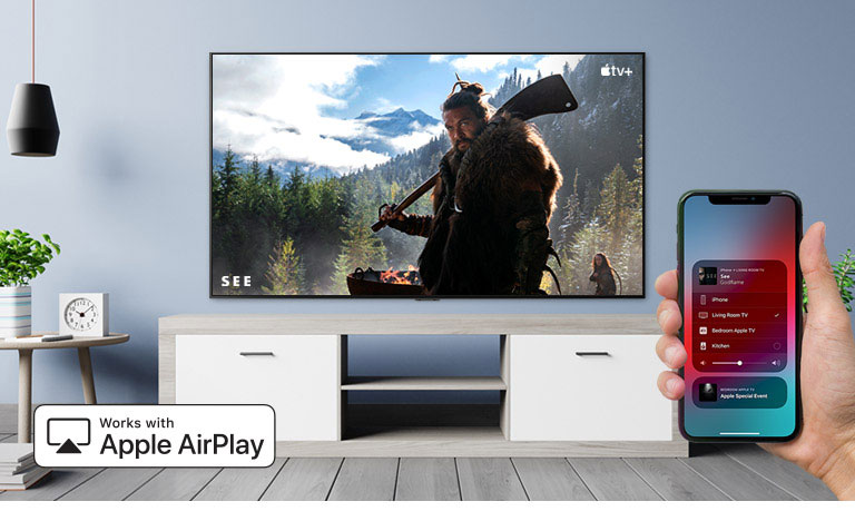 Prikaz izbliza ruke koja upravlja televizorom putem pametnog telefona iPhone i televizor koji prikazuje sadržaj Apple TV+