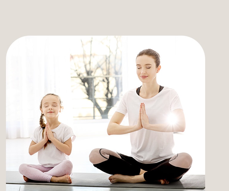 Majka i kćer meditiraju u dnevnoj sobi