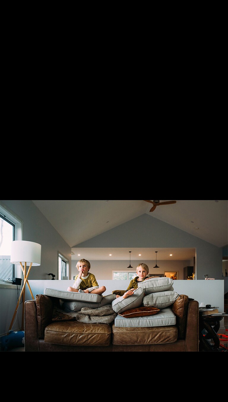 Dječaci blizanci gledaju nešto dok sjede na kauču.