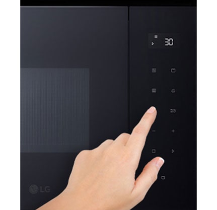 Dodirna ploča ugradbene mikrovalne pećnice i dodirni prst.