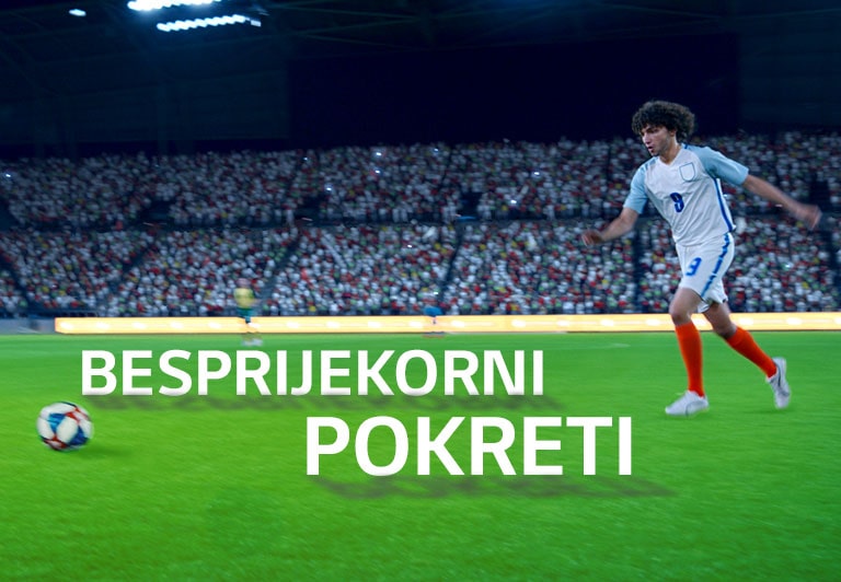 Četiri osobe sjede na kauču i gledaju televizor s velikim zaslonom na kojem se prikazuje nogometni stadion ispunjen gledateljima.