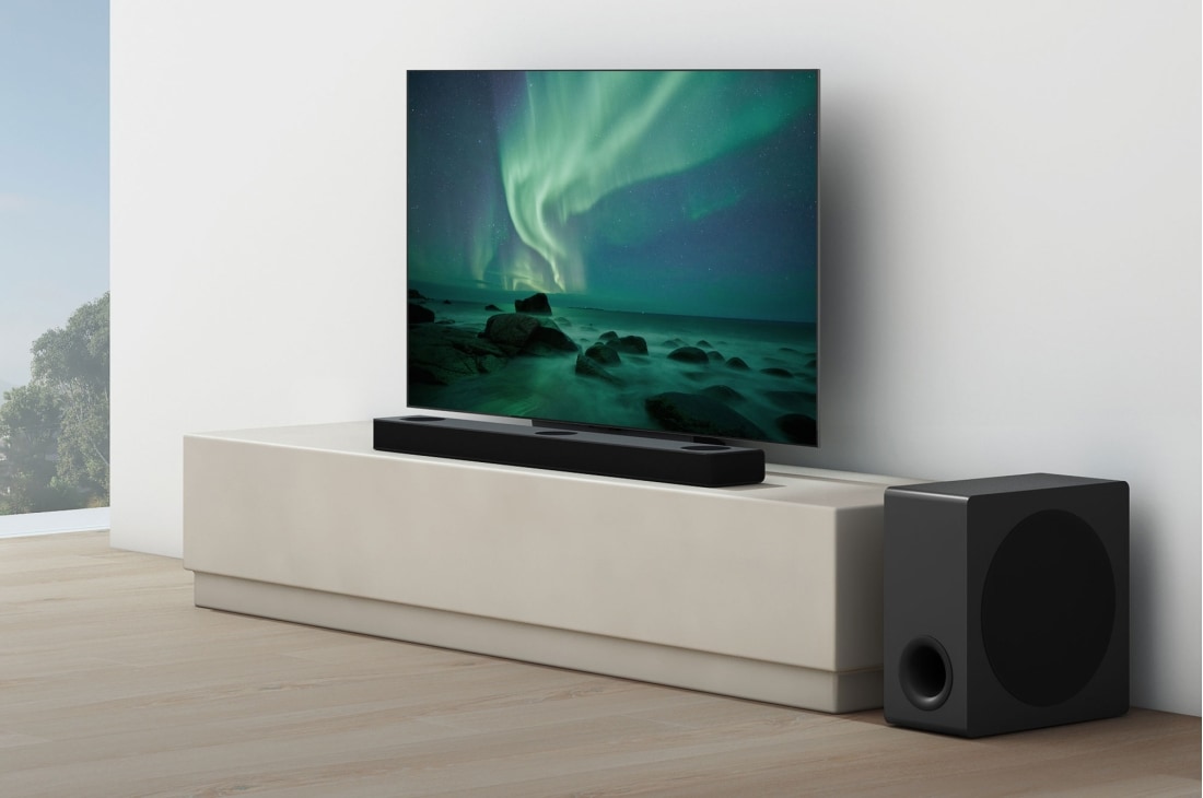 LG Soundbar S80QY, Zvučnik je smješten ispod televizora u bijeloj dnevnoj sobi, neposredno pored njega nalazi se niskofrekvencijski zvučnik., S80QY, thumbnail 5