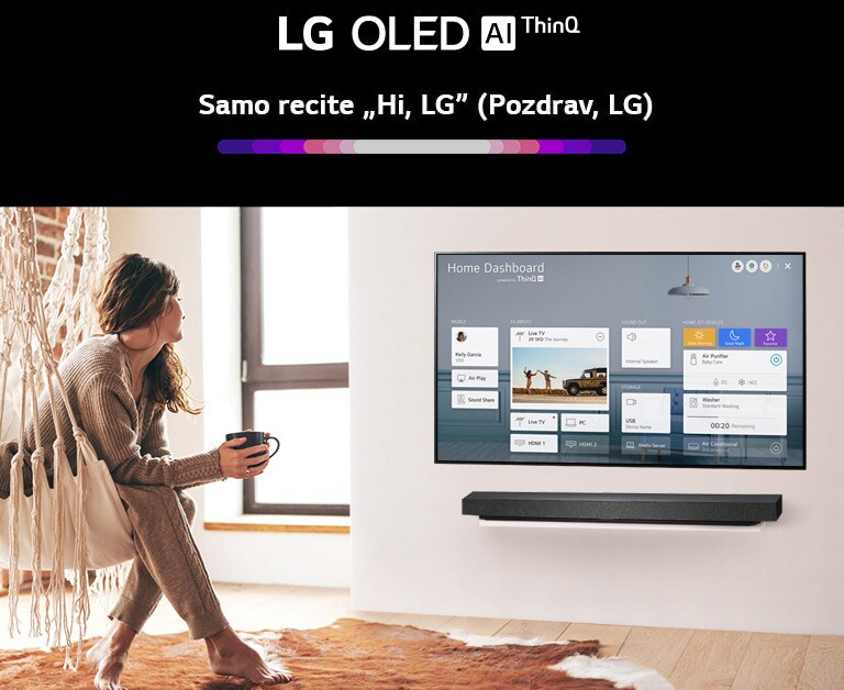 Žena sjedi na naslonjaču u dnevnoj sobi, a na zaslonu televizora prikazuje se kućna nadzorna ploča (Home Dashboard)