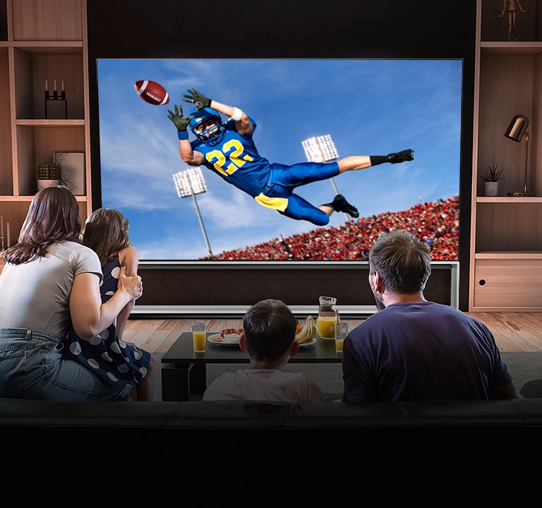 Ljudi koji gledaju utakmicu američkog nogometa na TV-u u dnevnoj sobi