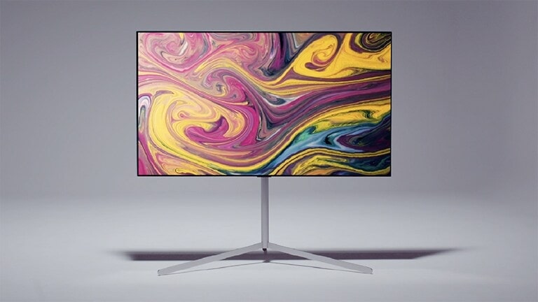 Dvije ruke nose bijele rukavice koje drže šipku galerijskog stalka, jedna se ruka stavlja blizu vrha, a druga blizu dna. Baza se stavlja na prateći nosač i istaknuta su različita udubljenja za prikaz kako možete podesiti visinu stalka. Koristi se vijak za fiksiranje stalka na mjesto. Zatim se baza stavlja na donji kraj šipke i pričvršćuje vijkom. TV se montira na prateći nosač tako da upada u rupe na nosaču i pričvršćuje vijkom na mjesto. Razvodnik s više kartica, usmjerivač i TV kutija pričvršćuju se na prateći nosač. Kablovi se vežu urednu da ne stoje na put i prijamnici se stavljaju u nogare stalka. Poklopac se stavlja da prekrije neke žice, a kamera zumira i otkriva predivni LG TV i galerijski stalak.