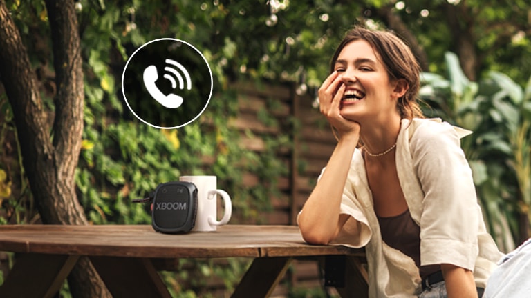 Žena razgovara telefonom putem LG XBOOM XG2 uređaja u načinu rada zvučnika.