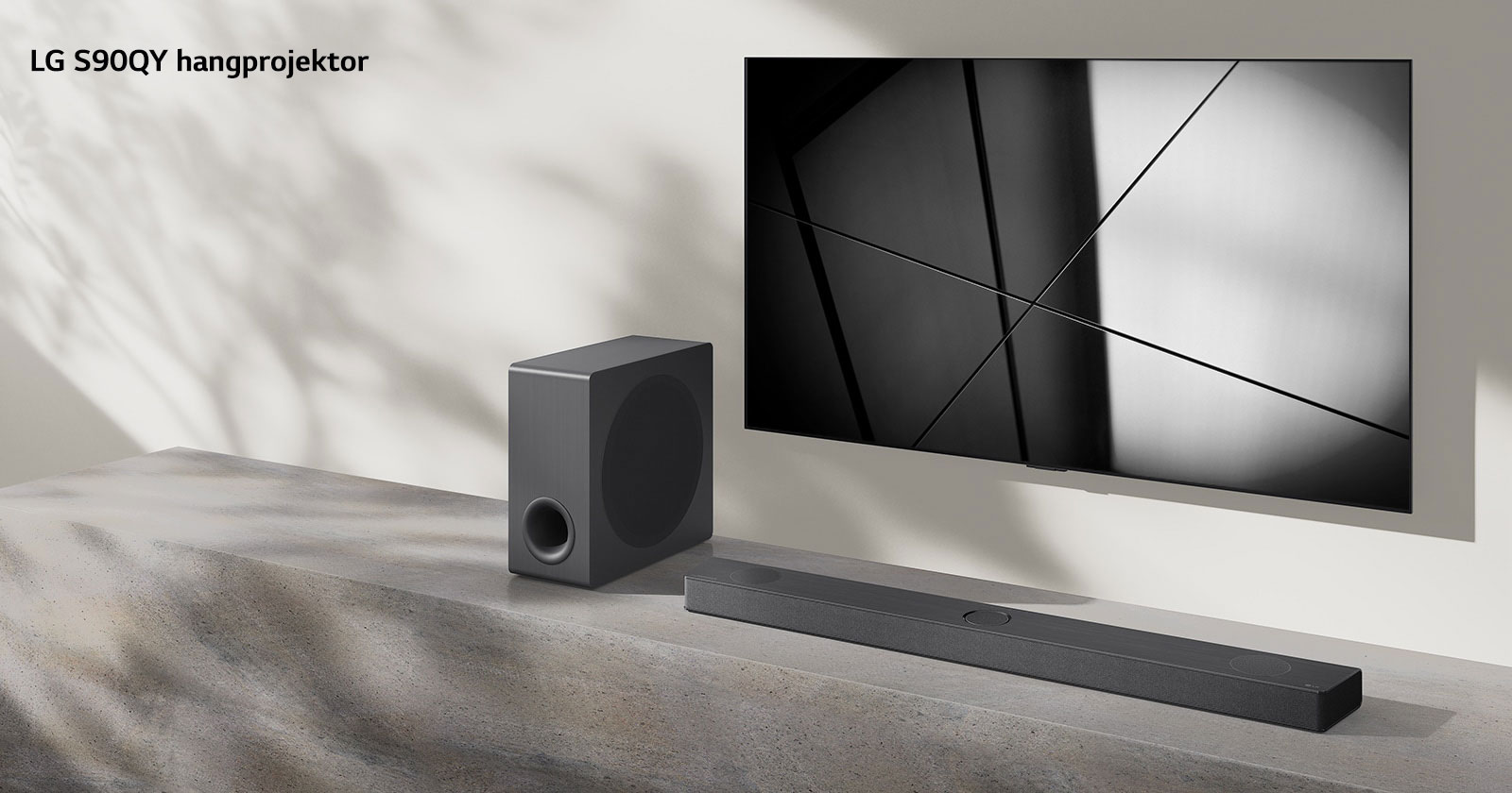 Egy LG S90QY hangprojektor és egy LG TV együtt egy nappaliban. A TV be van kapcsolva, és egy fekete-fehér kép látható rajta.