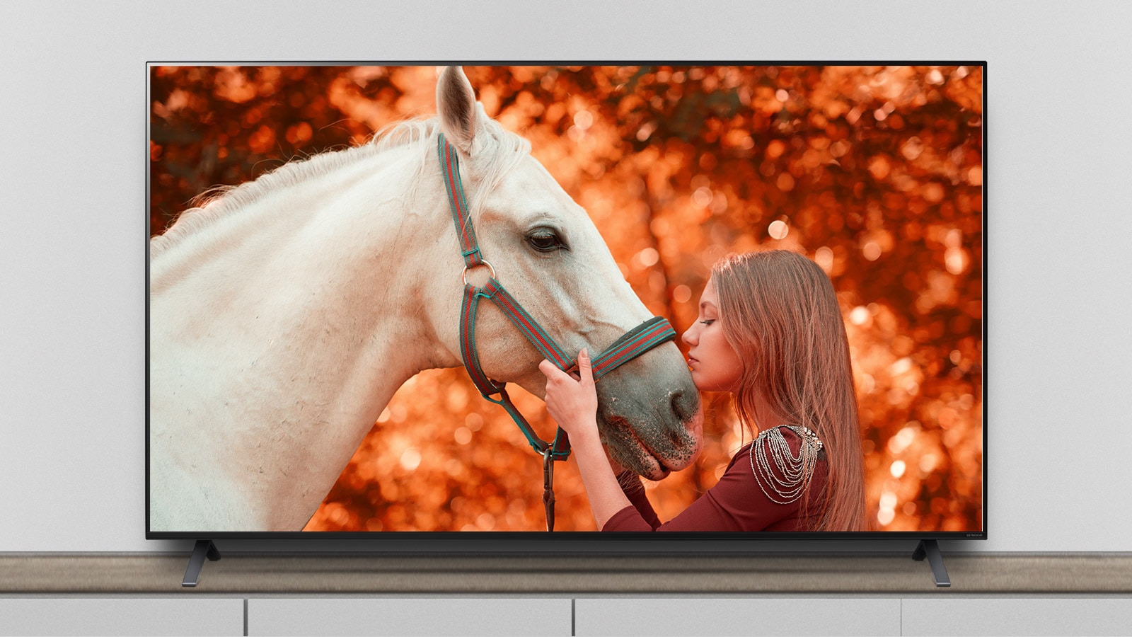 TV az állványon, és a képernyőn egy filmjelenet látható egy lóval és egy nővel.