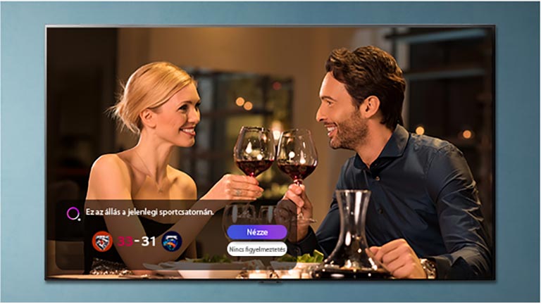 A man and a woman toast on a TV screen while a sports alert is displayed