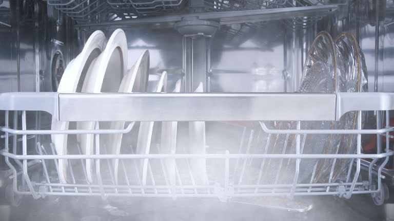 Egy megpakolt mosogatógép belseje látható, miközben magas hőmérsékleten történik a mosogatás.
