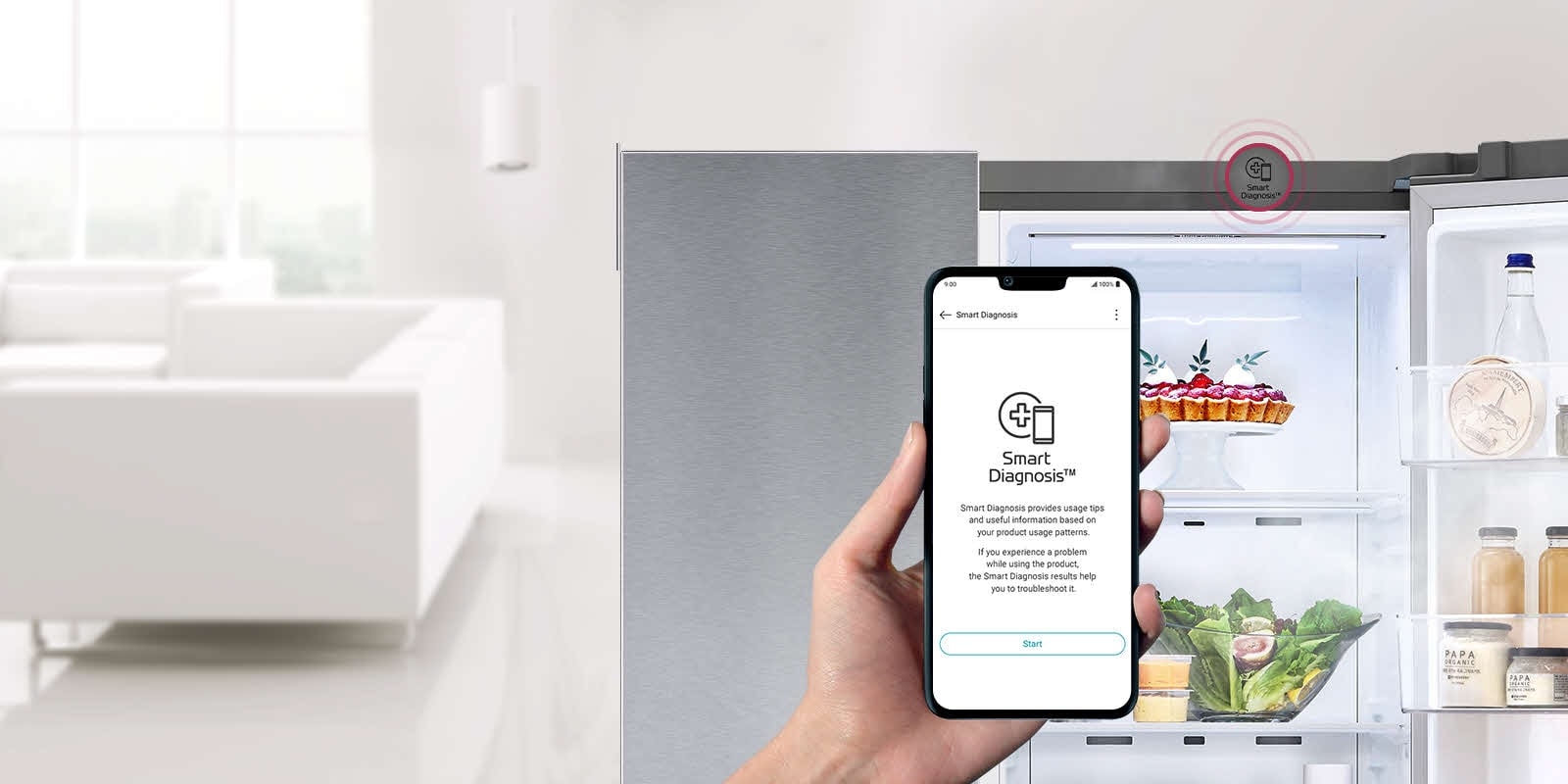 Egy kéz tartja a telefont. A telefon képernyőjén az LG ThinQ alkalmazás Smart Diagnosis funkciója látható. A háttérben lévő hűtőszekrény egyik oldala nyitva van, és a benne lévő tartalom látható. A hűtőszekrény tetején egy nagyobb Smart Diagnosis ikon található.