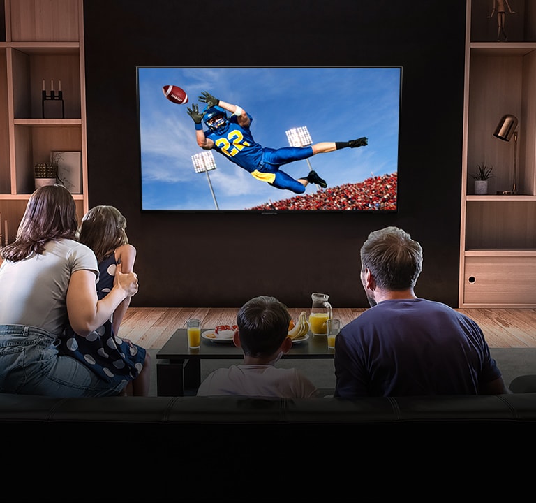 Az emberek egy amerikai futball játékot néznek a tévében a nappaliban