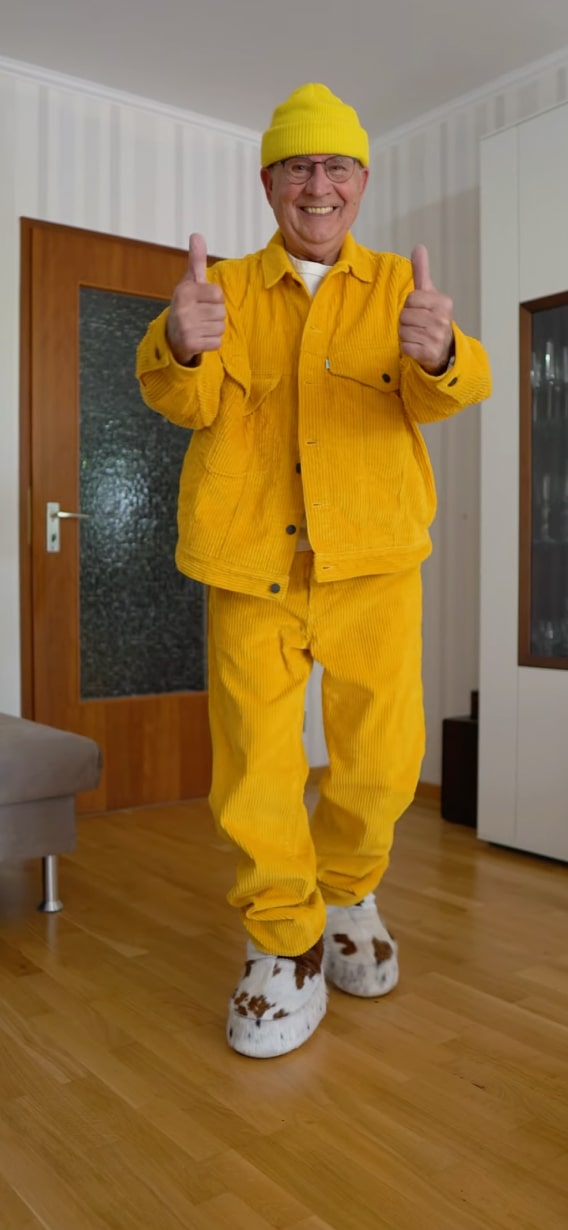 Man dressed in a bright yellow outfit giving thumbs up, showcasing confidence and joy.