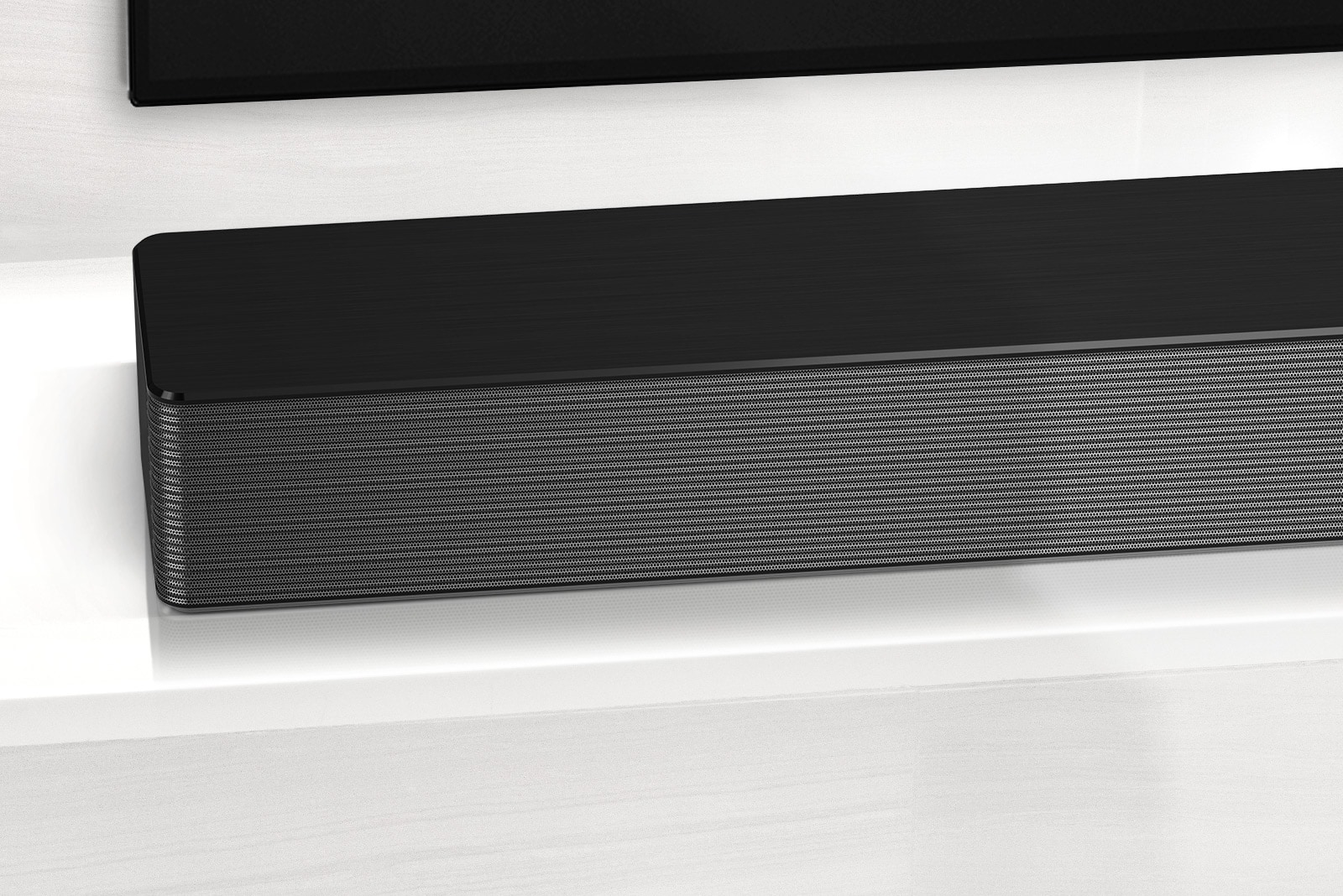 תקריב על הפינה השמאלית של LG Soundbar. רואים גם את החלק השמאלי התחתון של טלוויזיה. 