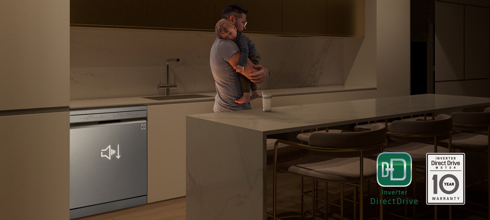 איש מחזיק תינוק ישן במטבח מואר באור עמום, מדיח כלים רצפתי פועל בשקט ברקע.