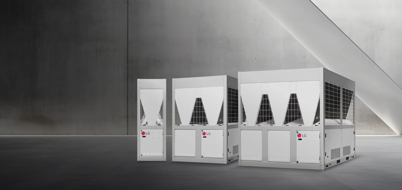 שלושה LG Inverter Scroll Chiller מוצגים בחלל מינימליסטי עם קירות בטון ותאורה רכה. 