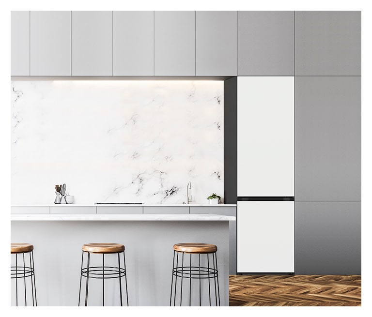 מוצג מקרר LG עם מקפיא תחתון מקולקציית Objet בצבע בז' ערפילי, ממוקם במטבח, התואם בטבעיות לרהיטים מסביב.