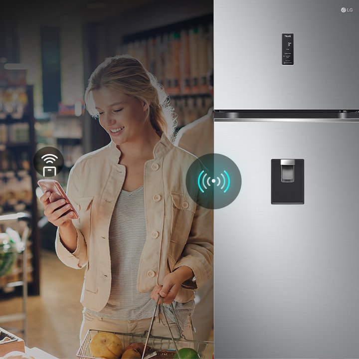 אישה שולטת במקרר LG מרחוק באמצעות הטלפון החכם שלה. התמונה מדגישה את הקישוריות החכמה של המקרר, המאפשרת למשתמשים לנהל ולהתאים את ההגדרות דרך המכשיר הנייד שלהם.