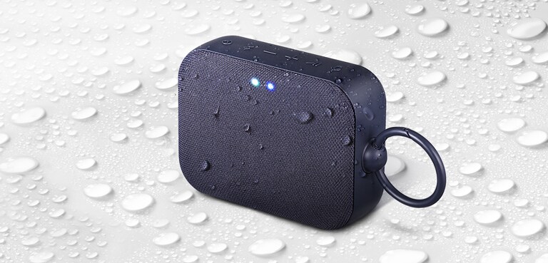 על רקע לבן, LG XBOOM Go PN1 פונה כלפי מעלה לצד שמאל. יש טיפות מים על רמקול LG XBOOM Go PN1 ומתחתיו.