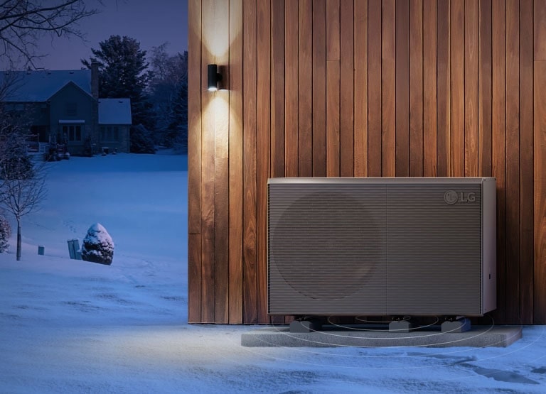 מוצרי LG THERMA V מוצבים מול קיר חיצוני של בית עץ, על רקע כפרים מושלגים.