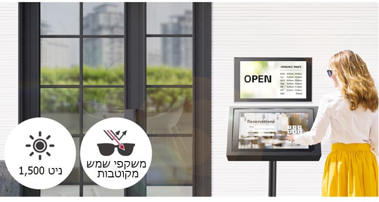 צג 22XE1J מותקן על הקיר בכניסה לבניין יחד עם צג 22XE1J נוסף עם מעמד המיועד למטרות הזמנה. האישה מרכיבה משקפי שמש ומשתמשת במסך 22XE1J עם כיסוי מגע כדי לבצע הזמנה. המסך בעל תצוגה גבוהה גם תחת אור שמש ישיר.