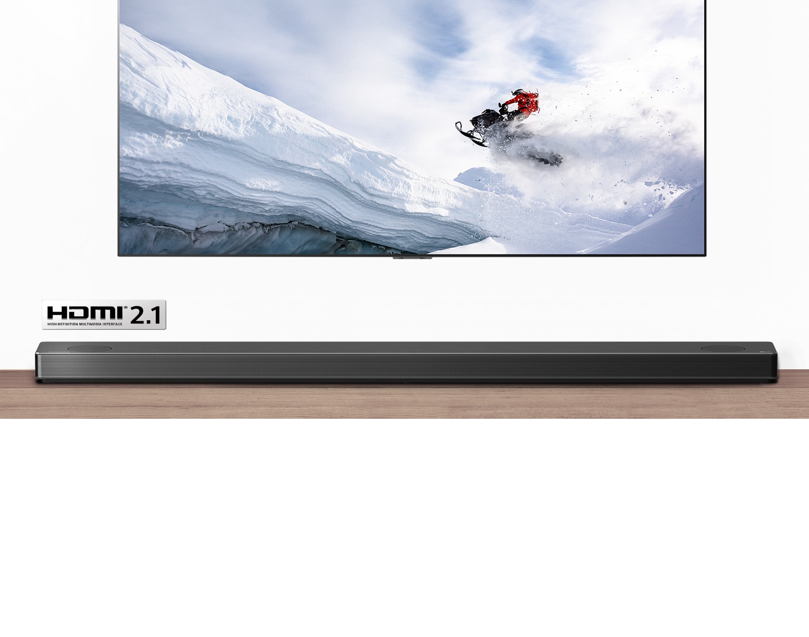 תצוגה של טלוויזיה וסאונד-בר מלפנים. טלוויזיה מציגה איש רוכב על אופנוע שלג בהרים המושלגים. הלוגו של HDMI 2.1 מופיע מתחת לטלוויזיה.