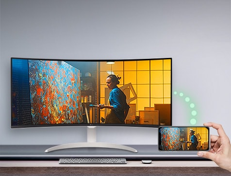 יש מסך המונח על השולחן, ומימין, טלפון המציג את אותו המסך כאשר המסך גלוי.