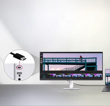 כבל USB Type-C המחובר בין מחשב נייד לצג רחב במיוחד של LG מציג ממשק עריכת וידאו, עם תקריב המראה את יציאת ה-USB-C בגב הצג.