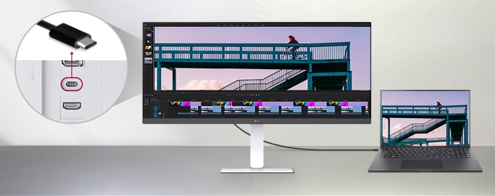 כבל USB Type-C המחבר מחשב נייד לצג רחב במיוחד של LG, עם תקריב המציג את יציאת ה-USB-C בגב הצג, לצד הצגת תוכנת עריכת וידאו הפועלת על שני המסכים.