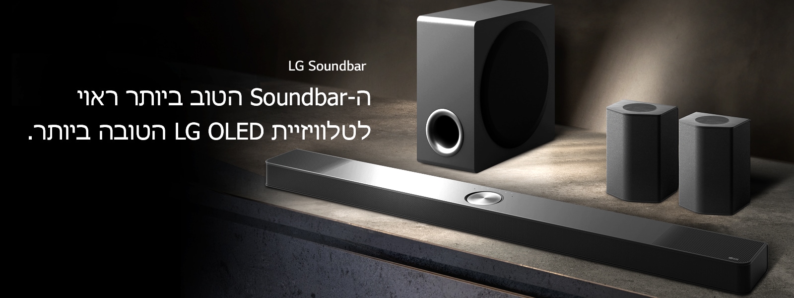 LG Soundbar, הרמקולים האחוריים והסאב-וופר ניצבים בפרספקטיבה זוויתית על מדף עץ חום בחדר שחור, מוחשך, עם אור מוטל רק על מערכת השמע.