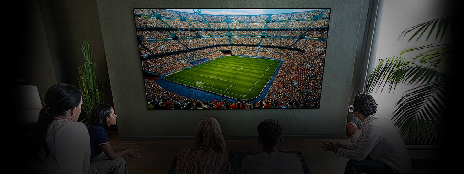 אנשים צופים במשחק כדורגל במסך ענק בחדר מגורים