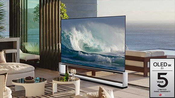 LG OLED Z2 מוצגת בחדר בעיצוב מינימליסטי מול חלון שמשקיף על עצי היער