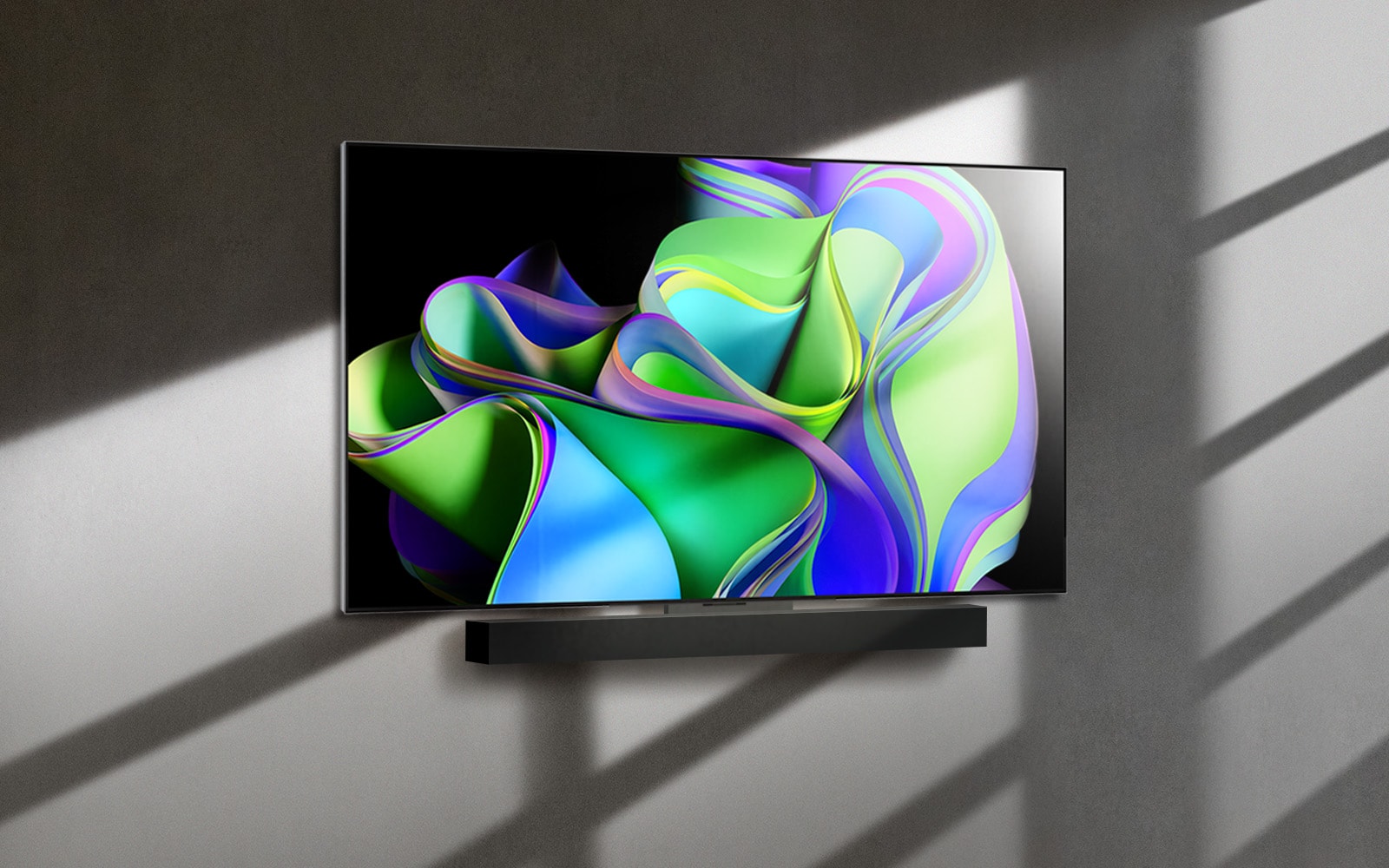 a video opens with the words lg oled evo against a black background. the words enlargen and fill with color. then the scene transitions to lg oled c3, showing a colorful abstract artwork with a soundbar against a white background. the white background becomes a wall in a room to which the tv attaches. 